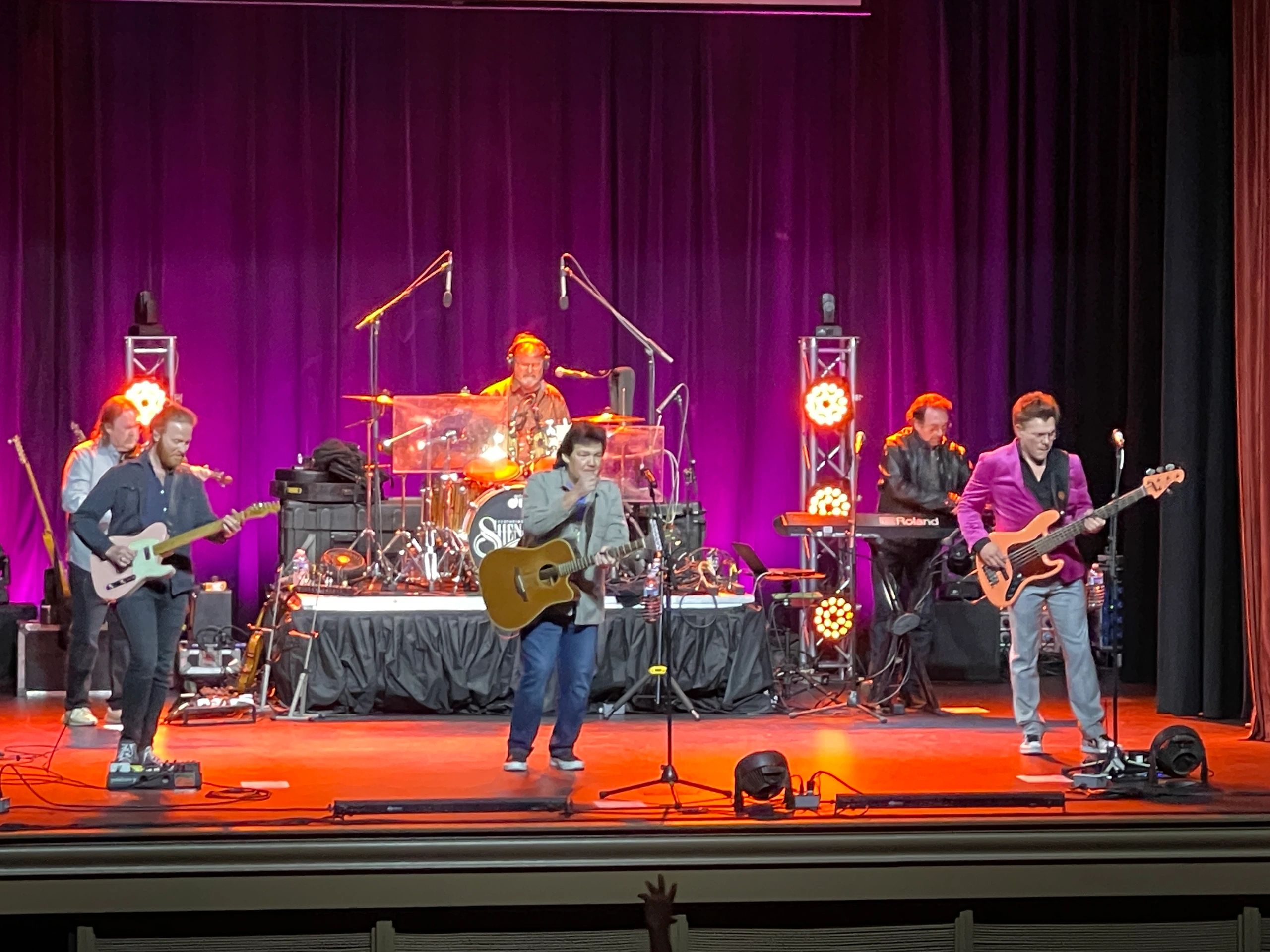Band performing with purple curtain backdrop